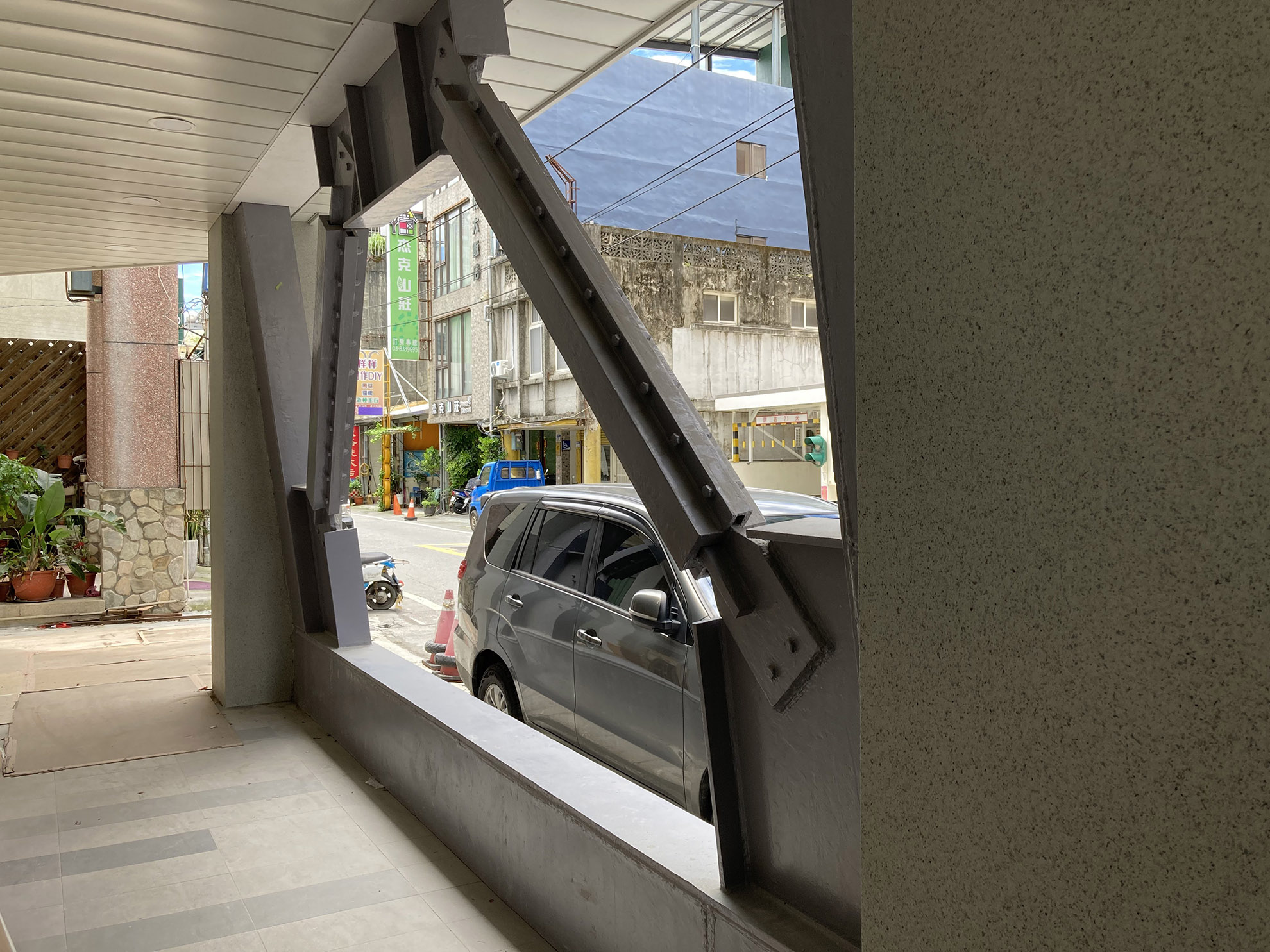 exemple d'un bâtiment (banque) renforcé depuis le séisme de 2018. coté rue, les poteaux sont renforcés par une structure métallique, sur le pignon, un chemissage de sportiques est visible. le bâtiment ne présente pas de dommage à la structure.